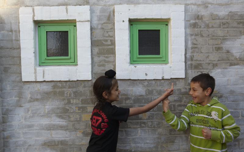 Dreng og pige ved to små grønne vinduer 