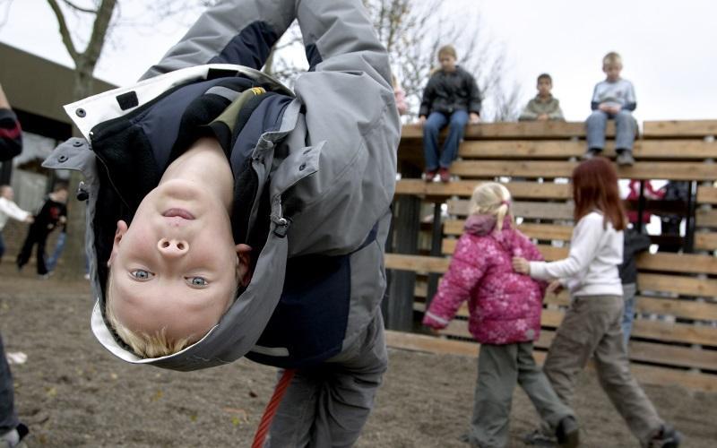 Dreng hænger på hovedet på legeplads