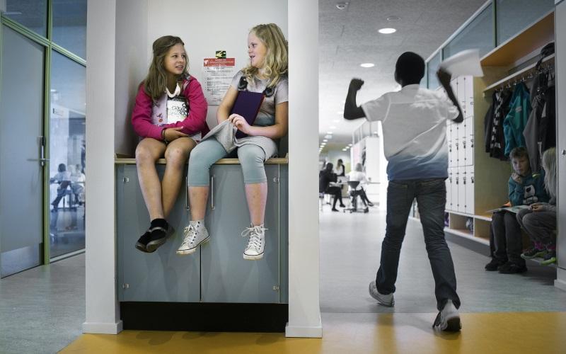 To piger sidder på bord på gang 