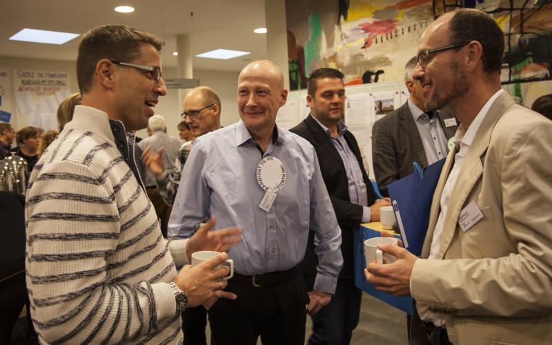 Tre mænd står og taler