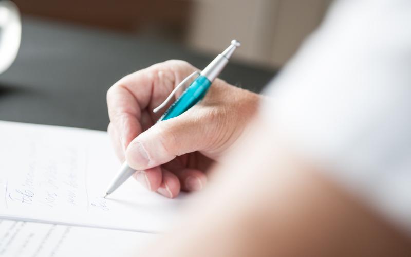 En person skriver på papir