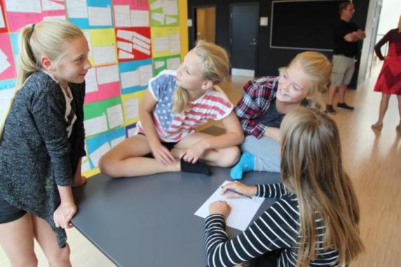 Elever står rundt om bord i skolen